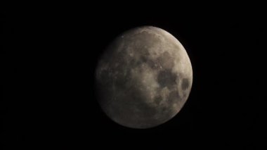 Moon before the full moon close-up on a black background of the night sky. Clouds passing by the Moon in spooky feeling like thriller and horror films