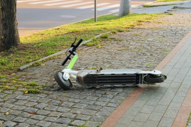 Electric scooter lies on the sidewalk in the city