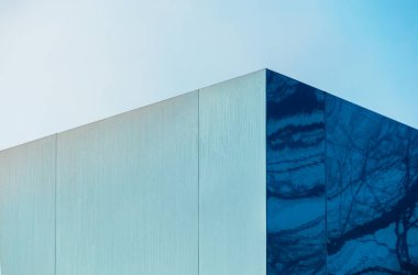 Modern building with a glass mirror facade against the blue sky. Bottom view of a modern skyscraper in a business district