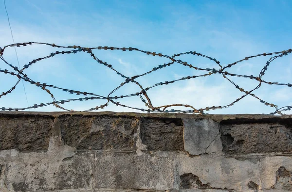 stock image Barbed wire on an old fence close-up against the sky, the perimeter of a prison or a barrier on the border from illegal migrants