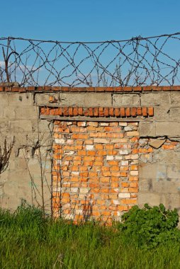 Dikenli telli eski duvar, kapalı geçit, kırmızı tuğlayla kapatılmış.
