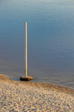 Suyun kıyısındaki kumlu sahilde bir demir çubuk borusu duruyor.