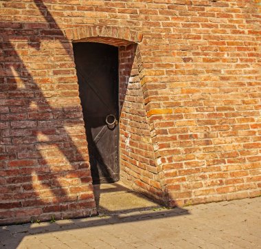 Kırmızı tuğlalı duvardaki eski demir kapı. Eski bir binanın, kalenin ya da kalenin dışında.