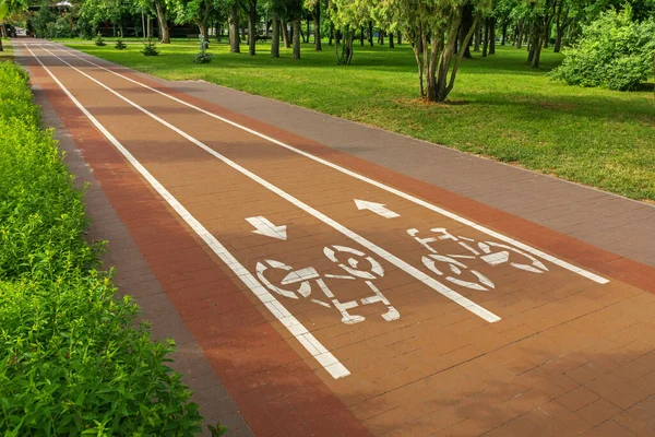 白い塗料の道路標識は 都市庭園や夏の日に公園内の路地に自転車道を示しています — ストック写真