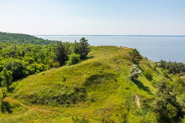 Pivikha Dağı ve Ukrayna 'daki Kremenchuk rezervuarı manzarası. Güneşli bir yaz gününde ağaçlı tepe