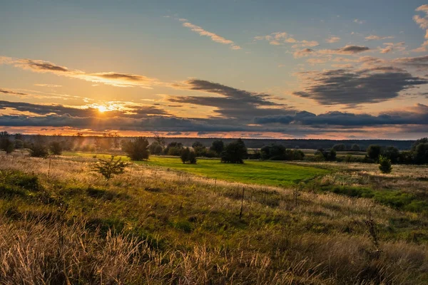 Nehir vadisindeki ağaçlarla dolu bir çayırda gün doğumuyla güzel bir manzara ve bir yaz günü bulutlarla dolu bir gökyüzü.