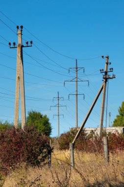 Beton sütunlar üzerinde kablolar şeklinde kablolar halinde, kırsal alanda açık mavi bir gökyüzünün zeminine karşı.