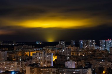 Doğanın ışık kirliliği - çok katlı binaların, kentleşme ve ekoloji sorununun olduğu bir şehrin üzerinde gece bulutlarında parlıyor