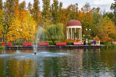 Kharkiv şehri, Ukrayna - 18 Ekim 2023: Sonbaharda güzel bir şehir parkında fıskiyesi, bankları ve çardağı olan pitoresk bir gölet