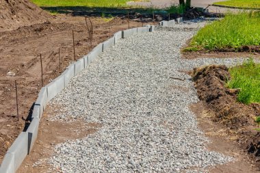 Caddelere ya da parka yaya yolu ve kaldırım inşaatı. Küçük taşlar halinde çakıl taşları yere dökülür.