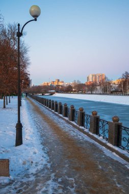 Lopan Nehri 'nin seti. Kharkiv şehrinde taş ve metalden yapılmış bir çit var. Soğuk bir akşamda kışın şehir manzarası