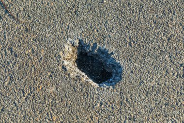 Asfaltta küçük bir delik. Asfalt kaldırımda bir delik. Yakın plan.