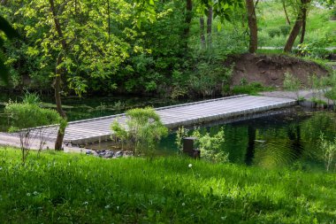 Ormandaki ya da bahçedeki küçük bir nehrin üzerindeki modern beton köprü. Su seviyesinde yaya köprüsü