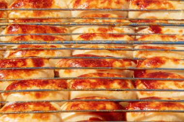 Tavuk sosisleri yakın planda kızartılır. Metal bir ızgarada dışarıda yemek pişirmek.