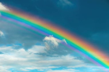 Gökyüzünde parlak ve resimsi bir gökkuşağı. Gökkuşağı, kırılma, iç yansıma ve su damlacıklarında ışığın dağılması sonucu gökyüzünde sürekli bir ışık spektrumunun oluşmasına neden olan optik bir olgudur.