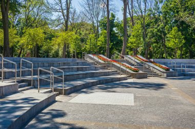 Güneşli bir yaz gününde parktaki ya da şehir bahçesindeki metal krom parmaklıklarla taş ayaklar ve merdivenler. Açık hava gösterisi ve konser yeri
