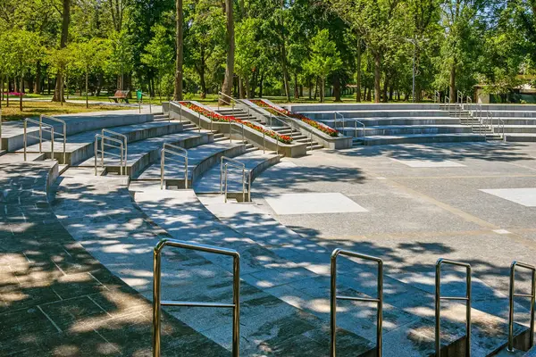 Güneşli bir yaz gününde, parktaki veya şehir bahçesindeki metal korkuluklu merdivenleri olan modern amfi tiyatrolar. Gösteriler ve konserler için açık hava mekanı. Kharkiv şehri, Ukrayna
