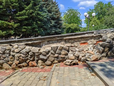 Şehir parkındaki büyük granit taşlardan oluşan bir duvar çöküyor. Taşlar düştü ve yaya yolunun yakınına düştü.