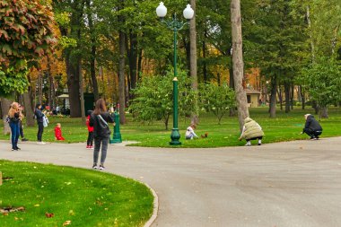 Kharkiv şehri, Ukrayna - 12 Ekim 2024: Parktaki insanlar bir sincabı izliyor. Şehir sakinleri parkta yürüyüşe çıktılar.