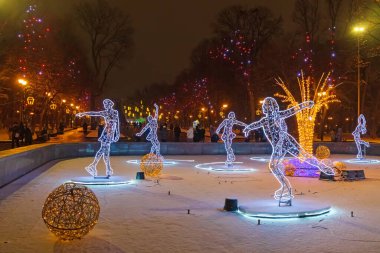 Kharkiv şehri, Ukrayna - 6 Aralık 2024: Artistik patinajcıların Kharkiv kentindeki Shevchenko 'nun adını taşıyan şehir bahçesinin çeşmesine yerleştirilmesi. Akşam parkta Noel süslemeleriyle