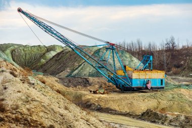 Maden ocağında yürüyen bir kılavuz kazıcı. Toprak ve mineral yığınları