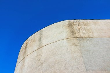 Beton duvarın kıvrımlı yüzeyi, açık mavi gökyüzünde çatlaklar var. Minimalist ve anıtsal mimariyle inşa ediliyor.