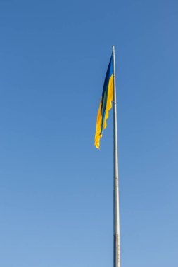 Yüksek bayrak direğinde Ukrayna bayrağı. Açık mavi gökyüzüne karşı ulusal Ukrayna bayrağı. Bayrak dalgalanmıyor, rüzgar yok.