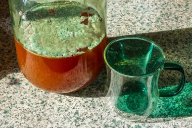 Cam kavanozda meyve suyu kalıbı ve masada cam bardak. Ev yemeği konservesi bozulmuş..