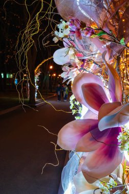 Yapay çiçeklerin, dalların ve elektrik ışığının bahar kompozisyonu - şehir bahçesindeki sokakta veya parkta dekoratif süslemeler
