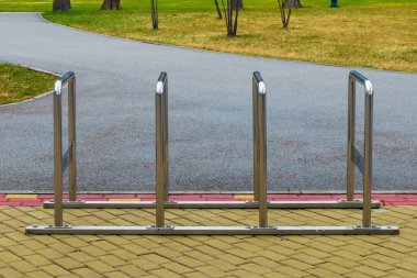 Asfalt yolda ya da kaldırımda krom bisiklet parkı. Metal açık hava bisikleti parkı