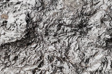 Kömür taşına yakın çekim. Kömür, kömür dikişleri adı verilen kaya tabakası olarak oluşturulan yanıcı siyah tortulu bir kayadır. Parlak yüzeyin makro fotoğrafı.