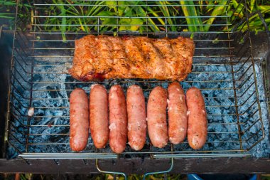 Domuz pirzolası ve sosisler sıcak kömürlerin üstünde kızartılır. Mangal 'da metal bir ızgarada et pişirme işlemi