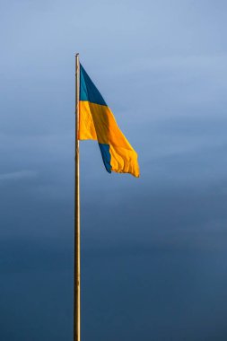 Yüksek bir bayrak direğinde Ukrayna 'nın büyük ulusal bayrağı. Gökyüzünde sarı ve mavi bayrak