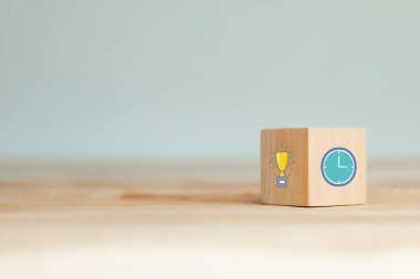 Tahta bir bloğun yakın plan görüntüsü bir kupa ve saat sergiliyor, başarıyı ve zaman yönetimini simgeliyor. Motivasyon içeriği için ideal.