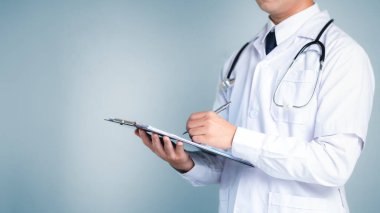 Beyaz önlüklü profesyonel bir doktor elinde bir dosya ve kalem tutarak hasta bakımı ve tıbbi uzmanlığın önemini vurgulayarak not almaya hazır bir şekilde arka planda duruyor..