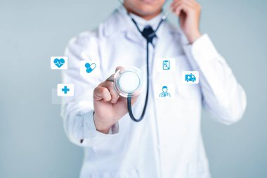 Steteskop takan bir doktor, sağlık hizmetleri teknolojisini temsil eden dijital tıbbi ikonlara bağlanıyor. Bu görüntü modern tıpta profesyonelliği ve hasta bakımında yeniliği aktarır..