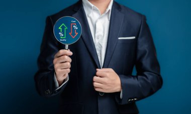 Takım elbiseli bir işadamı, elinde yukarı ve aşağı ok işaretli, finans analizini sembolize eden, kalite ve maliyet göstergeleri gösteren bir tabela tutuyor..