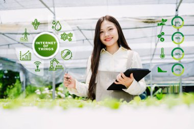 Genç bir kadın, sürdürülebilir tarım ve bitki gelişiminin etkin bir şekilde izlenmesi için IOT çözümleri sunan akıllı bir tarım ortamında teknolojiyle uğraşıyor..
