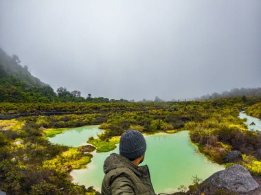 Purace, Cauca, Kolombiya 'daki gür doğa ve sisli dağlarla çevrili canlı San Juan kaplıcalarının nefes kesici manzarası..