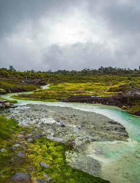 Purac, Cauca 'daki San Juan kaplıcalarının manzarası yemyeşil ve turkuaz suları bulutlu bir gökyüzü altında sergiliyor.