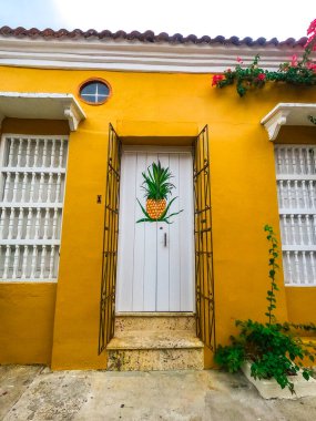 Kolombiya, Cartagena 'da güzel boyanmış bir ananas kapısının bulunduğu canlı sarı bir duvar.