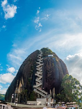 El Peol kayasının zirveye çıkan spiral merdiveniyle göz kamaştırıcı manzarası, Guatape, Antioquia 'da parlak mavi bir gökyüzüne karşı kurulmuş.