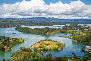 Bulutlarla dolu mavi bir gökyüzünün altında, Guatape, Antioquia 'nın yemyeşil adalarının ve canlı sularının çarpıcı hava manzarası.