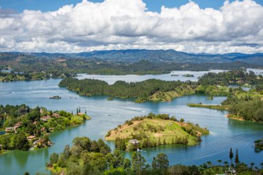 Tüylü bulutlarla dolu mavi gökyüzünün altında, Guatape, Antioquia 'daki yemyeşil adaların ve göllerin nefes kesici manzarası.