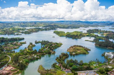 Kolombiya, Antioquia 'daki Guatape Gölü' nün nefes kesici hava manzarası parlak bir gökyüzü altında yemyeşil ve sakin suları sergiliyor.