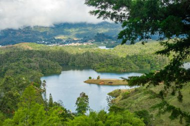 Guatape, Antioquia, Kolombiya 'daki yemyeşil yemyeşil ve dağlık arazilerle çevrili sakin bir göl manzarası.