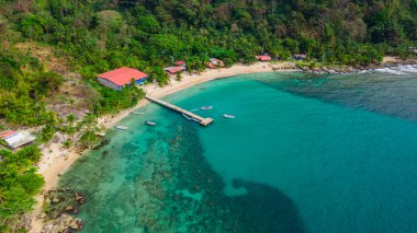 Sapzurro Sahili, berrak turkuaz suları, ahşap bir rıhtım ve yemyeşil çevresiyle göz kamaştırıcı bir hava manzarası. Kolombiya turizmi için mükemmel bir yer.
