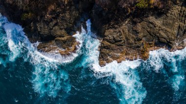 Sapzurro, Choco, Kolombiya 'da engebeli kayalara çarpan turkuaz dalgaların hava görüntüsü. Doğanın güzelliğini gözler önüne seren çarpıcı bir sahil manzarası
