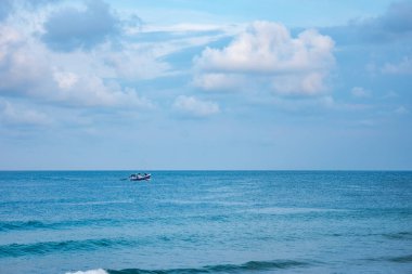 Okyanusun sakin manzarası Sapzurro, Choco, Kolombiya 'nın sakin sularında bulutlu bir gökyüzünün altında hareket eden bir tekne.