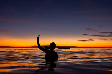 Sucre, Kolombiya 'da çarpıcı bir günbatımında Rincn del Mar' ın sakin sularının keyfini çıkaran bir kişinin silüeti.
